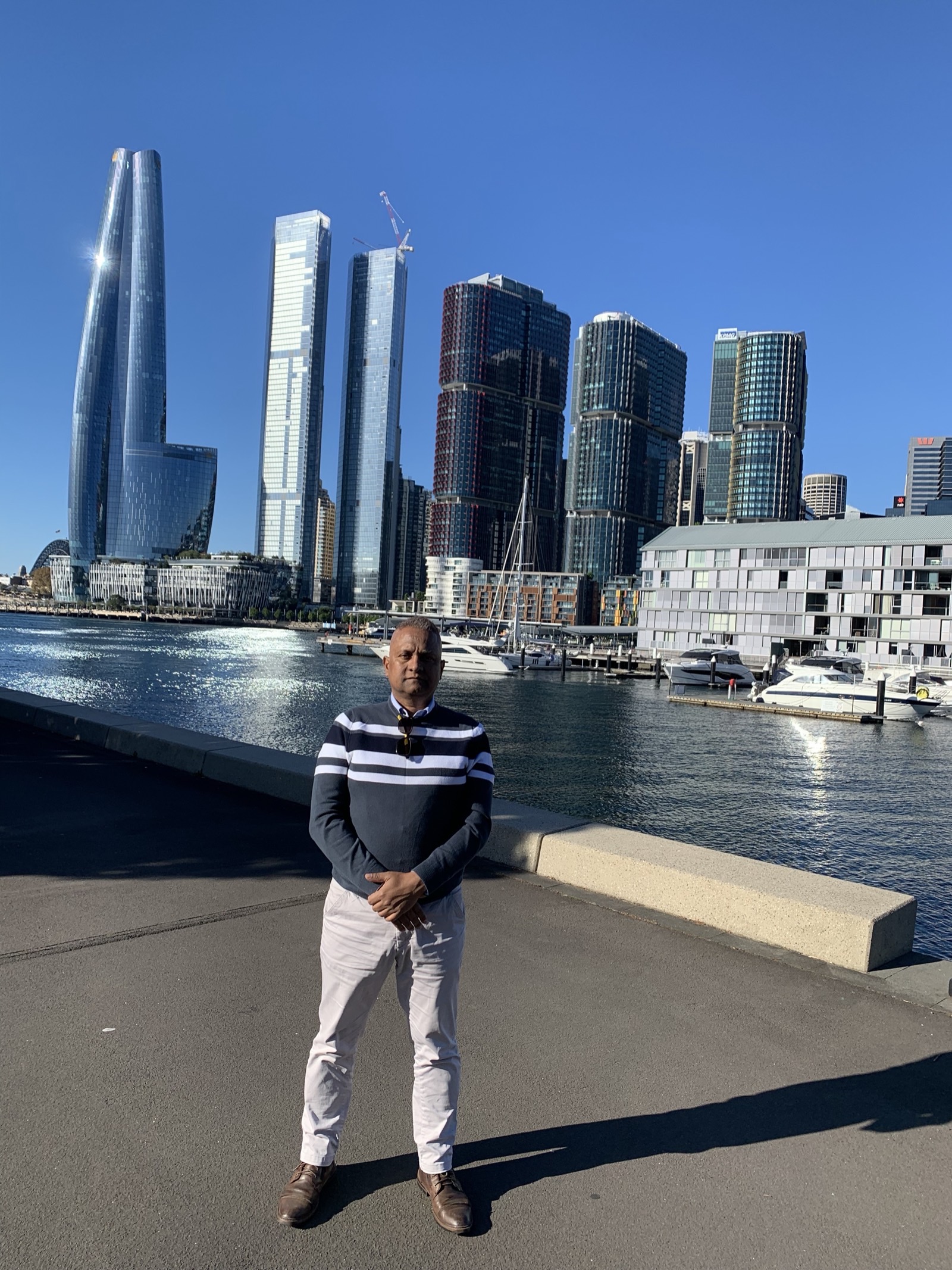 Mahendra Singh standing at Sydney Harbour, with the Barangaroo skyline behind him